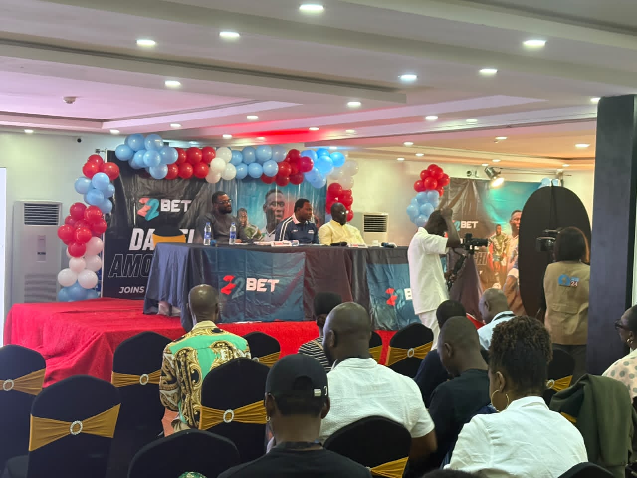 IMG-20260805-WA0008 - Nigeria Football Panel discussion on a stage with a blue tablecloth, sound equipment, and a backdrop reading ZBET, surrounded by red, white, and blue balloons; audience seated in rows.